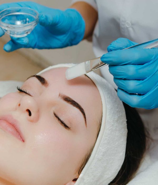 Beauty salon, cosmetician aplying facial peeling mask. Skin treatment concept.